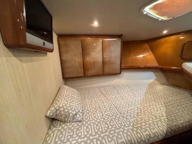 Slide: The Image of 2008 Ocean Yachts 54 Super Sport cabin with bed, TV, and wooden cabinets. - 29