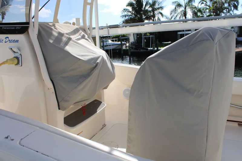 Slide: The Image of 2018 Grady-White Fisherman 257 boat interior with covered seats, docked near palm trees. - 14