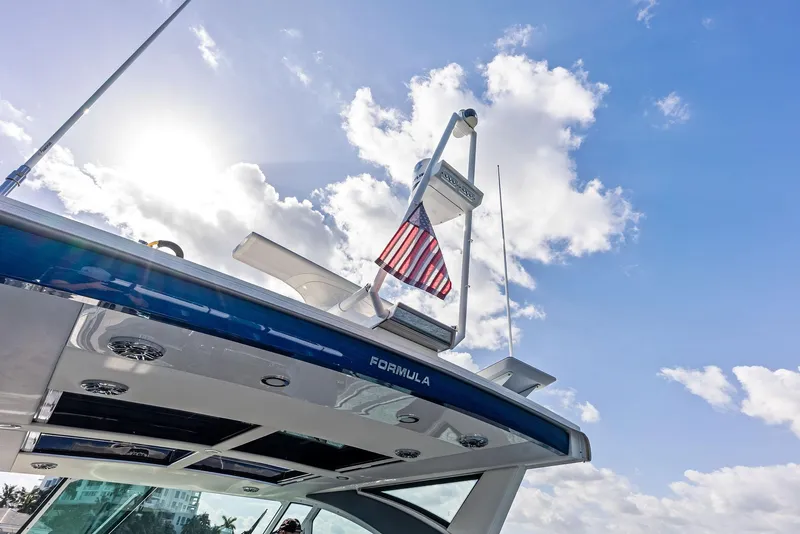 Slide: The Image of 2023 Formula 430 Super Sport Crossover boat with American flag under sunny sky. - 23