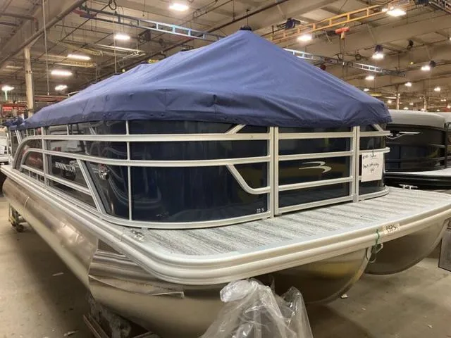 Slide: The Image of 2025 Bennington S L-Bench 21 SLJ pontoon boat with blue cover in a warehouse. - 3