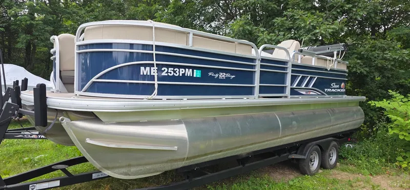 Slide: The Image of 2022 Sun Tracker PB 22 XP3 pontoon boat on trailer, surrounded by greenery. - 3