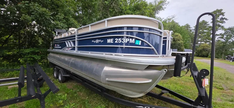 Slide: The Image of 2022 Sun Tracker PB 22 XP3 pontoon boat on trailer, parked near lush greenery. - 5