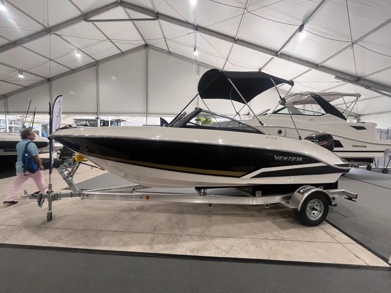 Slide: The Image of 2025 Ventura 195 Crossover boat displayed indoors on a trailer. - 2