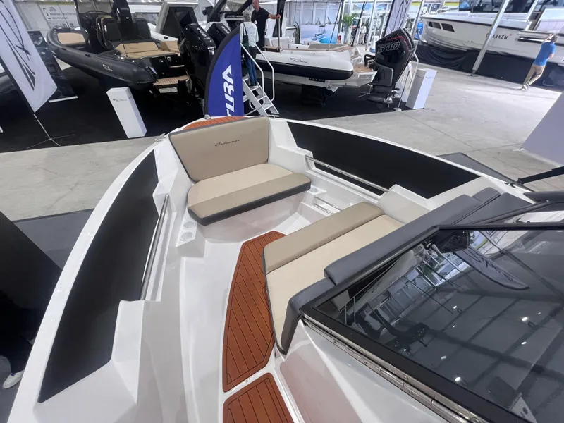 Slide: The Image of 2025 Ventura 195 Crossover boat interior with seating and wood accents at a showroom. - 34