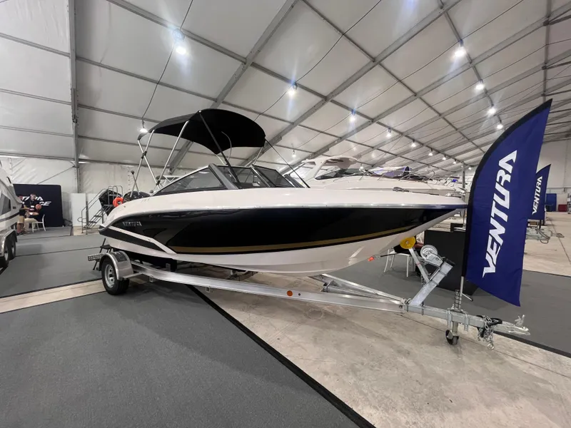 Slide: The Image of 2025 Ventura 195 Crossover boat displayed indoors on a trailer with a canopy. - 5
