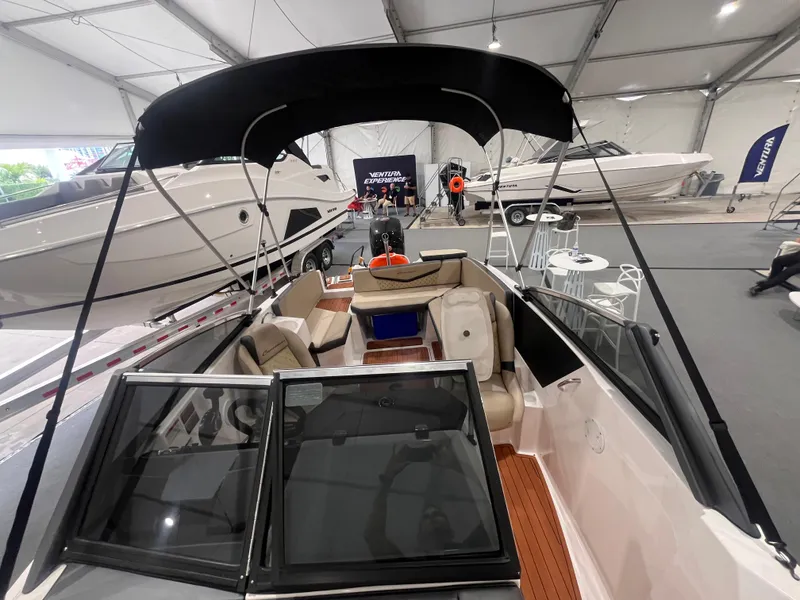 Slide: The Image of 2025 Ventura 195 Crossover boat displayed indoors with seating and canopy. - 51