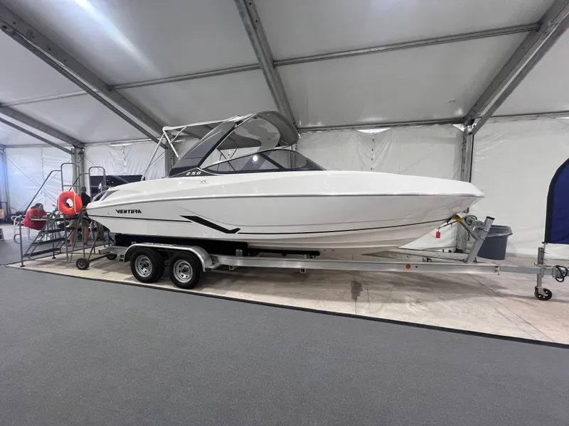 Slide: The Image of 2025 Ventura 252 Comfort boat displayed indoors on a trailer. - 1