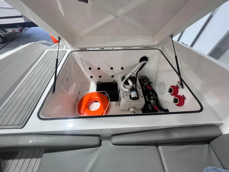 Slide: The Image of 2025 Ventura 252 Comfort boat storage compartment with safety equipment and mechanical components. - 12