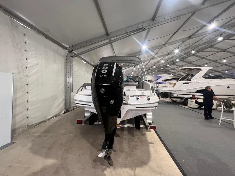 Slide: The Image of 2025 Ventura 252 Comfort boat displayed indoors with powerful outboard motor. - 3