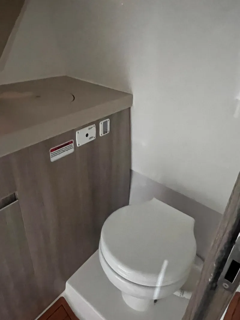 Slide: The Image of 2025 Ventura DayCruiser bathroom interior with compact toilet and wooden cabinetry. - 13