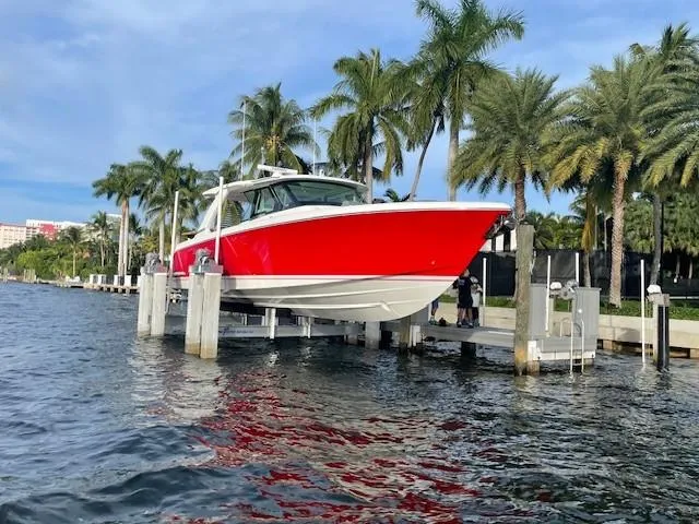 Slide: The Image of 2023 Tiara Yachts 48 LS in vibrant red, docked by palm trees. - 12