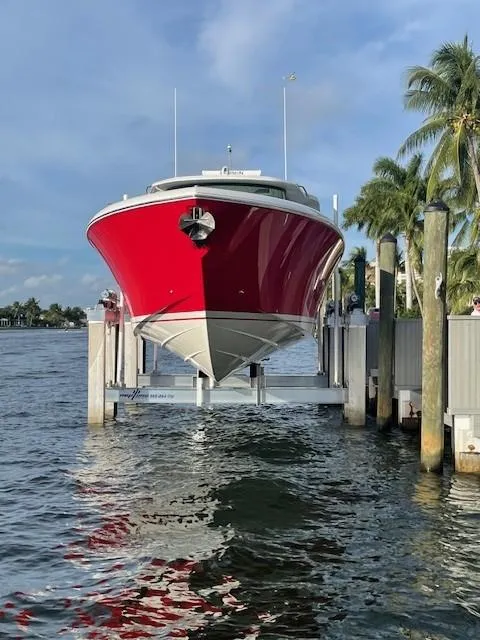 Slide: The Image of 2023 Tiara Yachts 48 LS in vibrant red, docked by palm trees. - 13