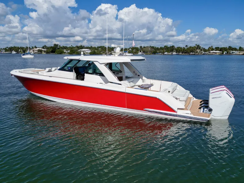 Slide: The Image of 2023 Tiara Yachts 48 LS in vibrant red, cruising on a sunny day. - 2