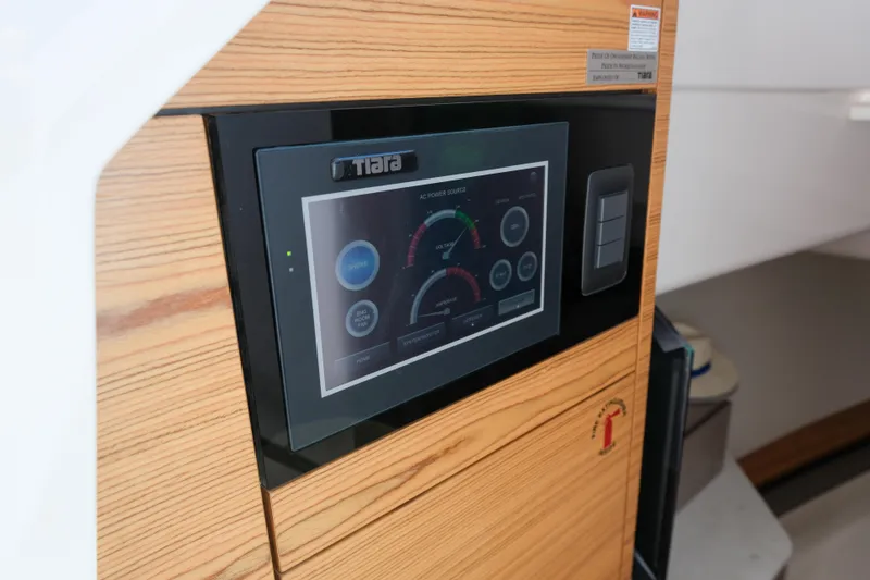 Slide: The Image of 2023 Tiara Yachts 48 LS control panel with digital display and wooden finish. - 42