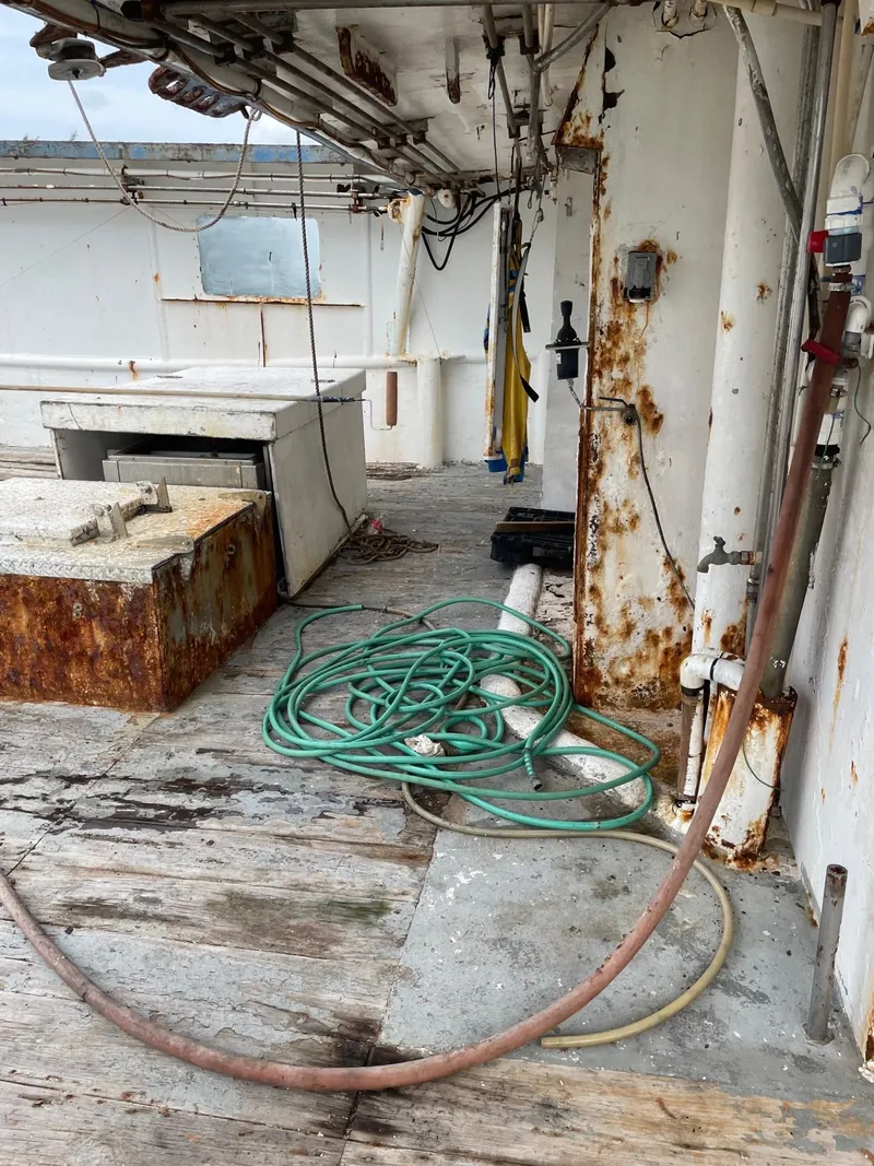 Slide: The Image of 1983 Commercial Freezer Trawler deck with weathered wood and storage compartments under cloudy sky. - 25