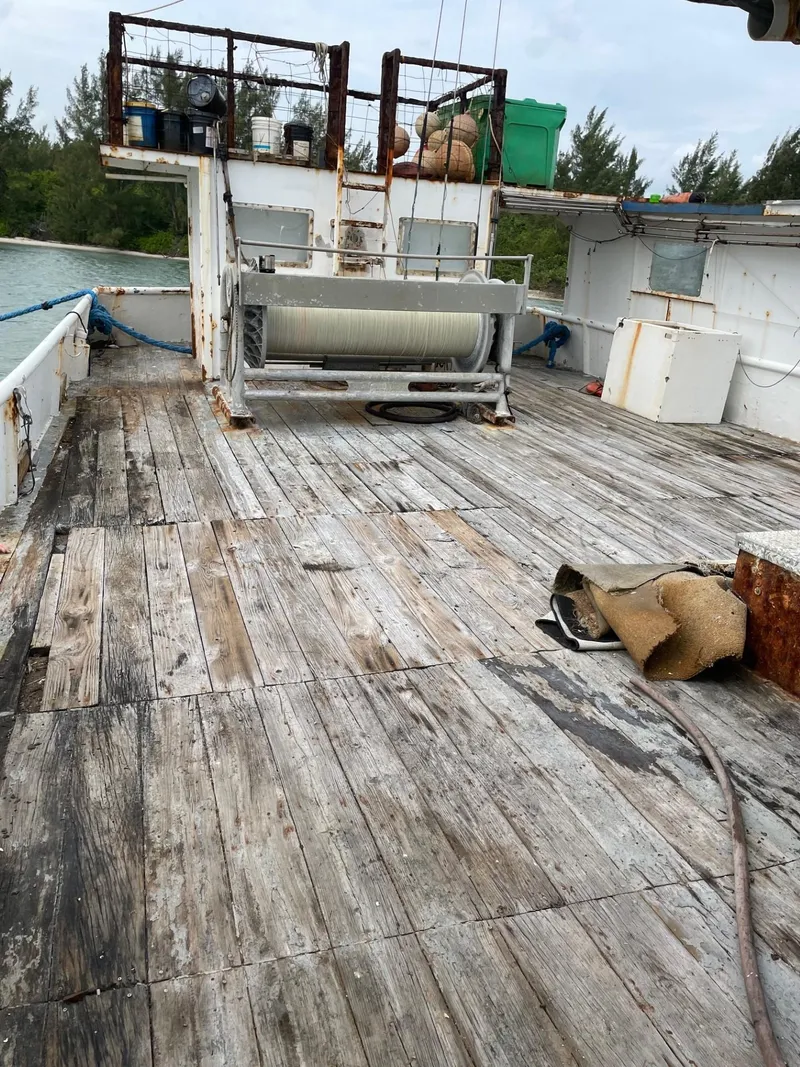 Slide: The Image of 1983 Commercial Freezer Trawler deck with equipment, weathered wood, and ocean backdrop. - 27