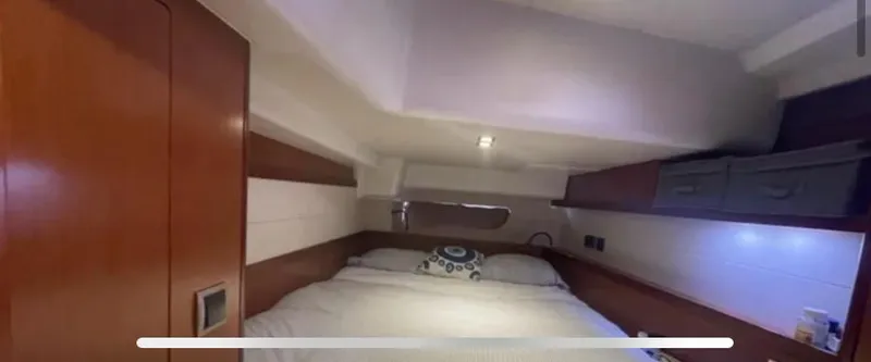 Slide: The Image of Interior cabin of 2011 Beneteau Oceanis 58 yacht, featuring a cozy bed and wooden accents. - 5