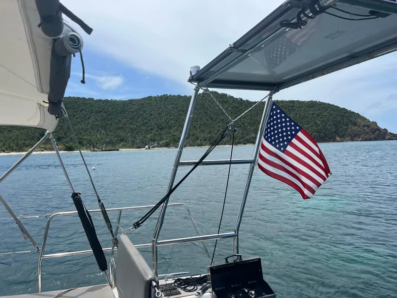 Slide: The Image of Beneteau Oceanis 58 sailboat, 2011 model, with American flag, anchored near lush coastline. - 8