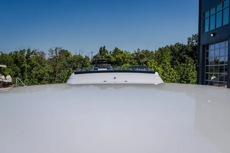 Slide: The Image of 2023 Cigarette 515 boat with sleek design, parked outdoors near trees and building. - 6
