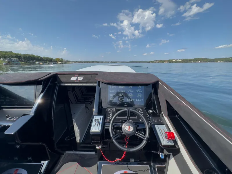 Slide: The Image of Cockpit view of 2023 Cigarette 515 boat on a calm lake under a clear sky. - 24