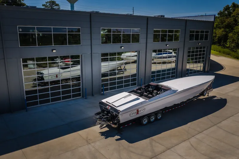 Slide: The Image of 2023 Cigarette 515 boat parked outside a modern garage with glass doors. - 14