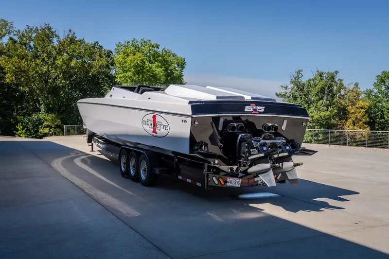 Slide: The Image of 2023 Cigarette 515 powerboat on trailer, parked outdoors with trees in background. - 22