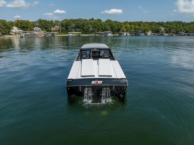 Slide: The Image of 2023 Cigarette 515 boat cruising on a serene lake with lush green shoreline. - 9