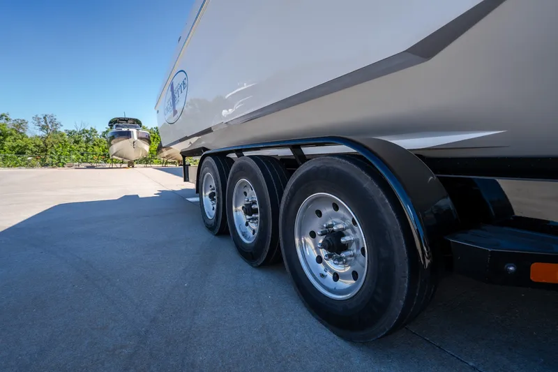 Slide: The Image of 2023 Cigarette 515 boat on trailer, showcasing triple-axle wheels in sunny outdoor setting. - 12