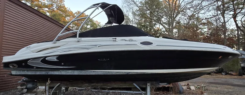 The Image of 2006 Sea Ray 270 Sundeck boat on a trailer, black and white design, outdoor setting. - 0