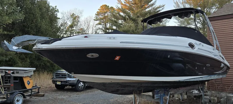Slide: The Image of 2006 Sea Ray 270 Sundeck boat on a trailer, surrounded by trees and vehicles. - 3