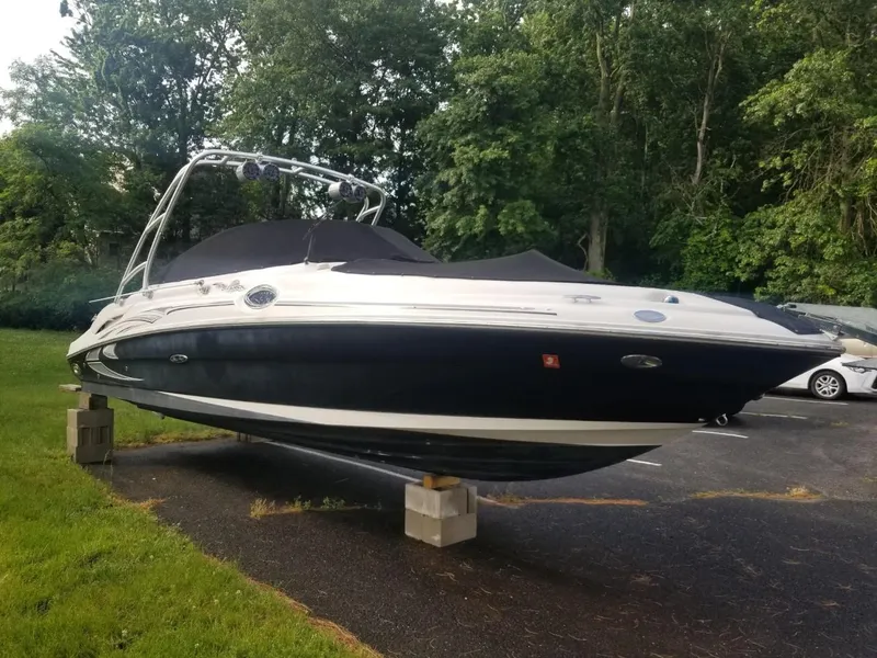 Slide: The Image of 2006 Sea Ray 270 Sundeck boat on blocks, parked outdoors near trees. - 8
