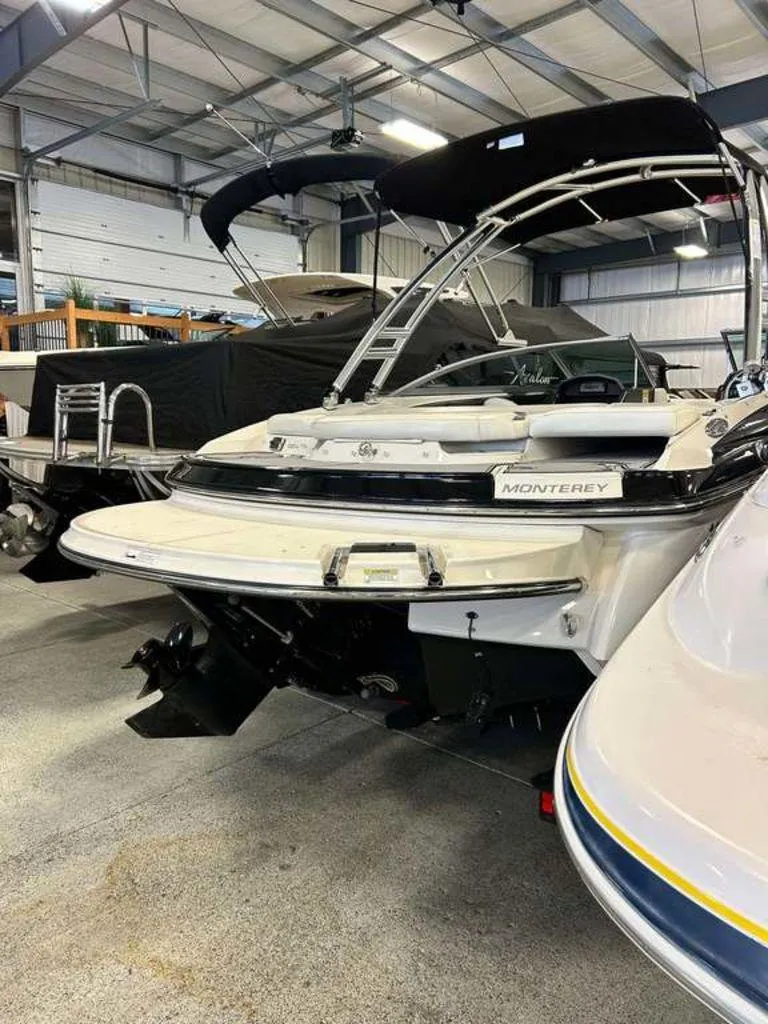 Slide: The Image of 2014 Monterey 224FSX boat in indoor storage, rear view with black canopy. - 11