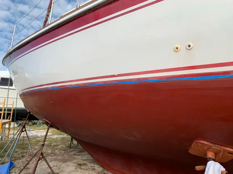 Slide: The Image of 1980 Wellington 44 Cutter Center Cockpit sailboat on dry dock, red and white hull. - 2