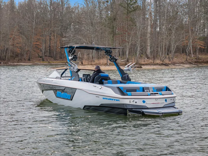 Slide: The Image of 2021 Malibu Wakesetter 25 LSV boat on a lake with wooded shoreline. - 0