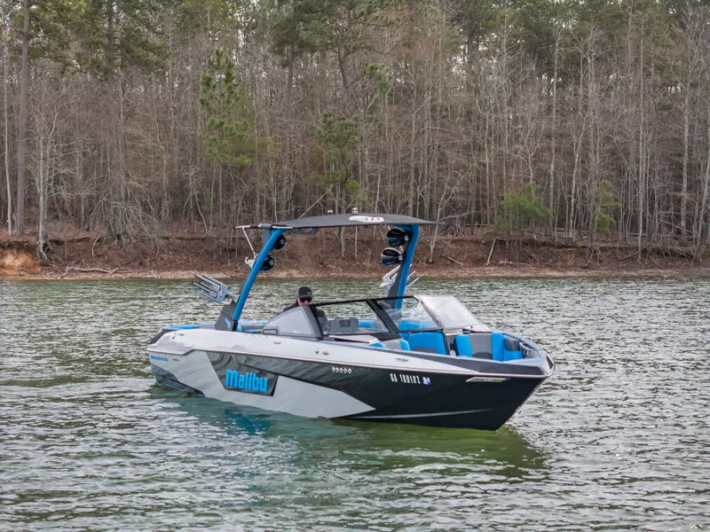 Slide: The Image of 2021 Malibu Wakesetter 25 LSV boat on a lake with forested background. - 1