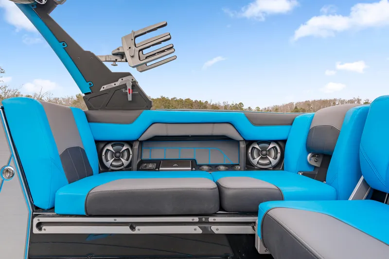 Slide: The Image of 2021 Malibu Wakesetter 25 LSV interior with blue and gray seating, speakers, and wakeboard rack. - 7