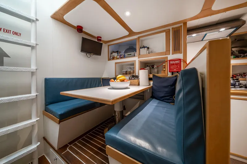 Slide: The Image of Cozy dining area in a 2007 MCP Tri-Deck yacht with blue seating and wooden accents. - 50