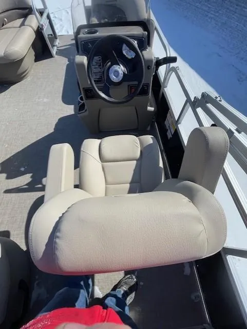 Slide: The Image of 2025 Sun Tracker Party Barge 16 DLX interior with beige seating and steering console. - 2
