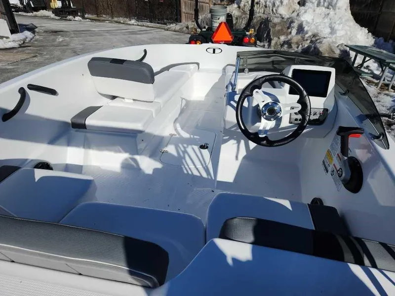 Slide: The Image of 2025 Tahoe T16 boat interior with steering wheel and seating in a snowy setting. - 2