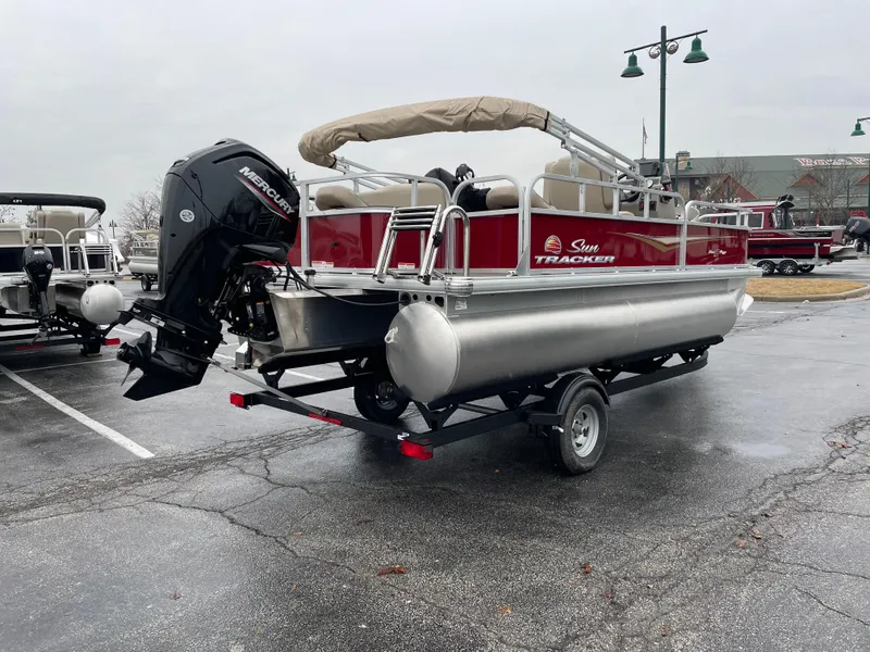 Slide: The Image of 2025 Sun Tracker Bass Buggy 18 DLX pontoon boat on trailer, parked outdoors. - 3