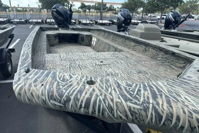 Slide: The Image of 2025 Tracker Grizzly 1650 T Prairie Wings Edition boat with camouflage design in a parking lot. - 4