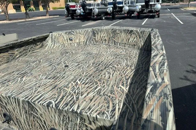 Slide: The Image of 2025 Tracker Grizzly 1650 T Prairie Wings Edition boat with camouflage design in a parking lot. - 9