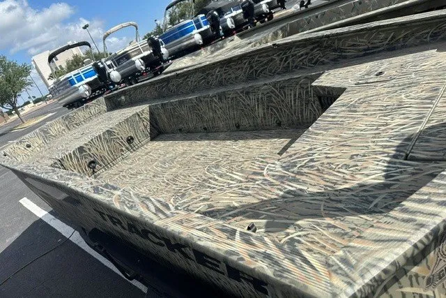 Slide: The Image of 2025 Tracker Grizzly 1650 T Prairie Wings Edition boat with camouflage design in a parking lot. - 7