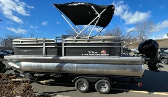 Slide: The Image of 2025 Sun Tracker Party Barge 20 DLX pontoon boat on trailer, under blue sky. - 2