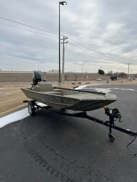 Slide: The Image of 2025 Tracker Grizzly 1648 SC boat on trailer, parked outdoors under cloudy sky. - 2