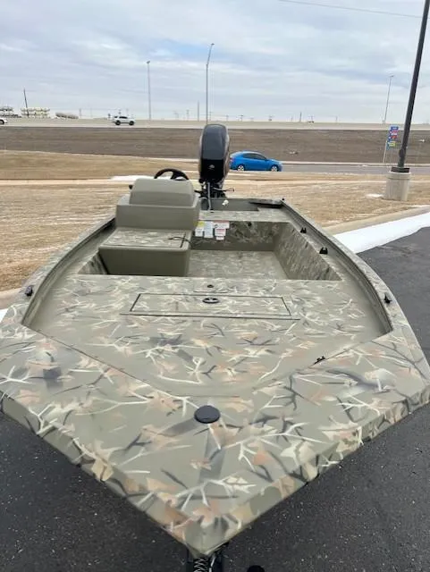Slide: The Image of 2025 Tracker Grizzly 1648 SC boat with camouflage design, parked outdoors. - 5