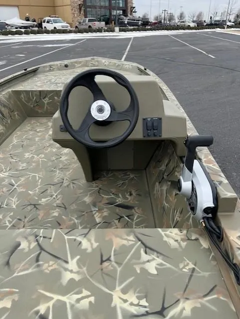 Slide: The Image of 2025 Tracker Grizzly 1648 SC boat with camouflage interior in a parking lot. - 8