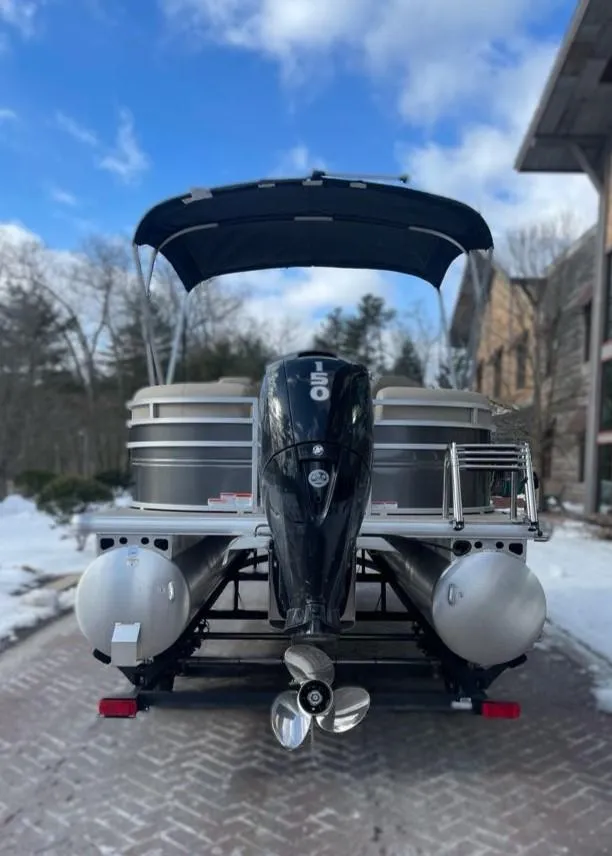 Slide: The Image of 2025 Sun Tracker Party Barge 22 DLX pontoon boat with canopy and motor, parked on snowy driveway. - 5