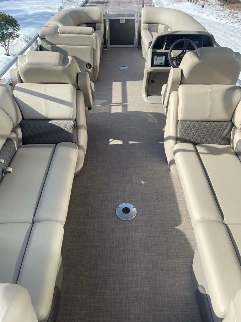 Slide: The Image of 2025 Sun Tracker Party Barge 22 DLX interior with beige seating and steering console. - 7