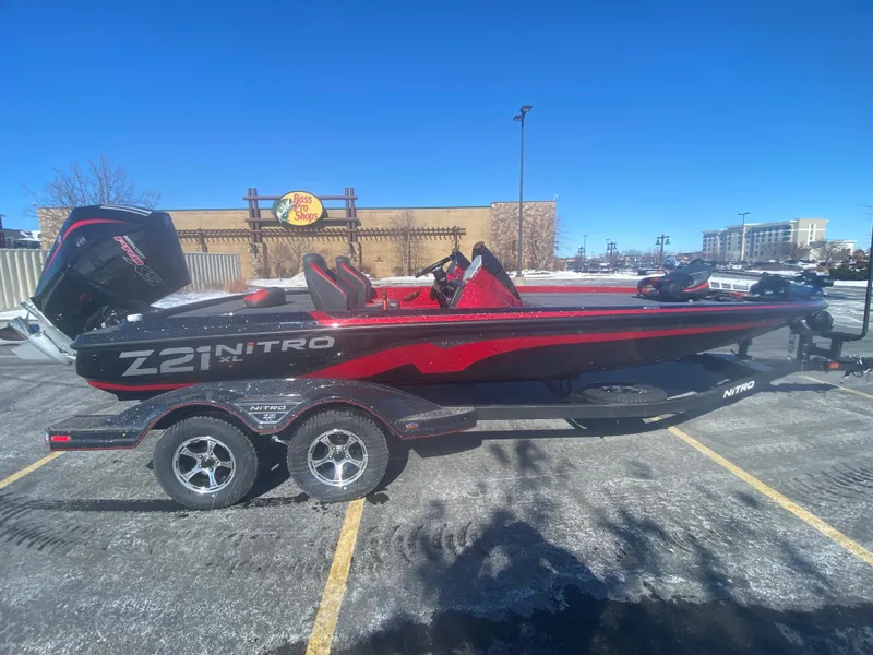 The Image of 2025 Nitro Z21 XL Pro boat in parking lot, red and black design, on trailer. - 0